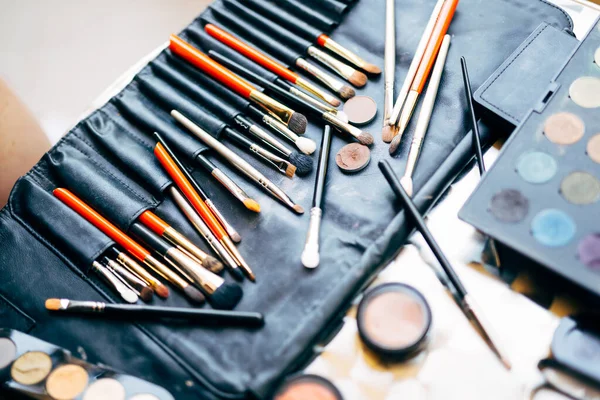 Truccatore impostato. Un set professionale di pennelli per il trucco e una tavolozza di ombretti di diversi colori in una borsa cosmetica nera. — Foto Stock