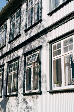 İki katlı, plastik pencereli, yuvarlak kaplamalı beyaz bir bina..