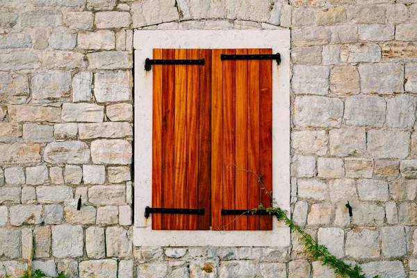 A brick wall with a window opening and new wooden shutters. — Stock Photo, Image