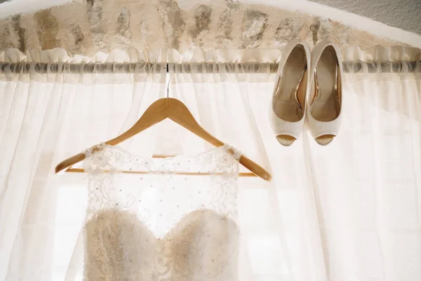 Holzanhänger mit Brautkleid am Gesims und Hochzeitsschuhen. — Stockfoto