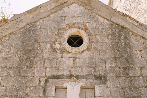Close-up of the round window of the monastery with the brides wedding dress at the entrance.