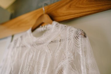 Gelinlerin yakalarının yakın çekimi duvara karşı ahşap bir askıya takılır..