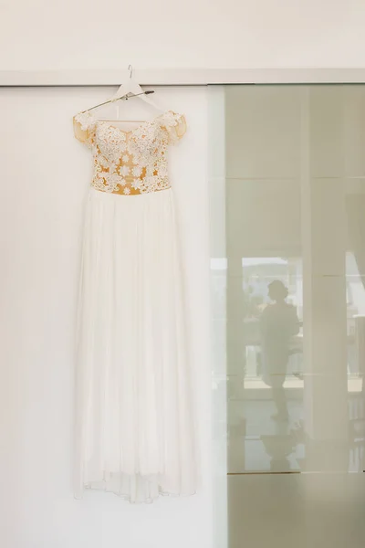 Vestido de novia blanco con un corsé de encaje en una percha con lavanda sobre un fondo de textura brillante con el reflejo de la figura de las novias. —  Fotos de Stock