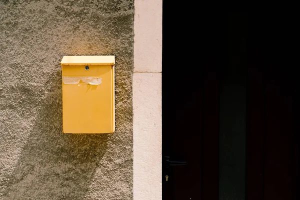 Ein gelber Briefkasten an einem sonnigen Tag auf einer Steinmauer in der Nähe der Haustür. — Stockfoto