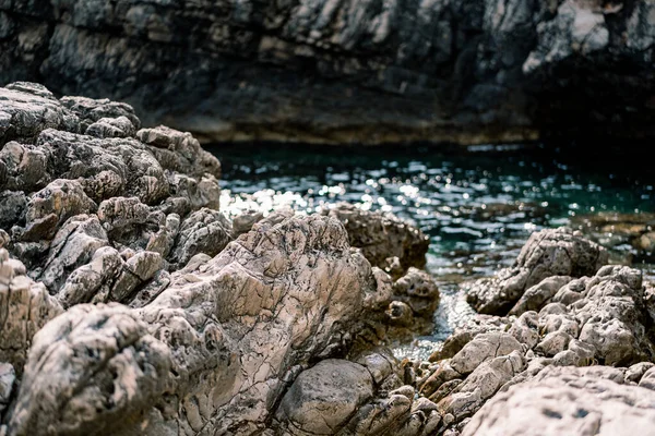 Rocallosas rocas masivas cerca de agua de mar azul y montañas. — Foto de Stock