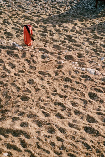 Inventario de salvavidas rojo en una playa de arena y guijarros. — Foto de Stock