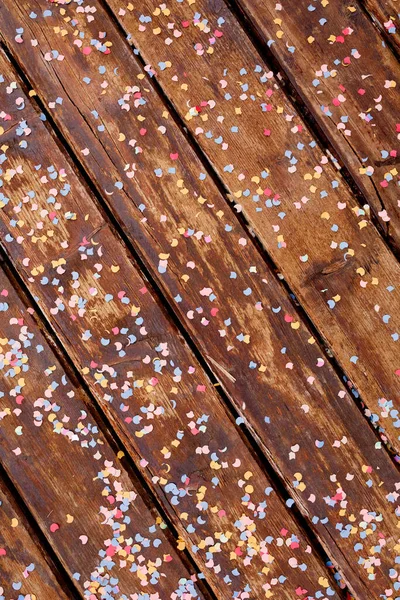 Brown wooden planks strewn with multicolored confetti in the shape of the moon and stars. — Stock Photo, Image