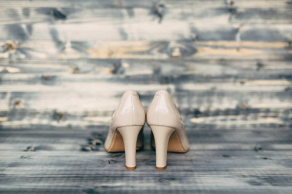Zapatos de dama de honor de tacón alto beige con textura de madera gris. —  Fotos de Stock