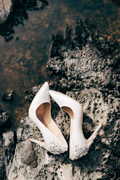 Kvinnors grädde brud skor med ädelstenar, på den steniga stranden. — Stockfoto