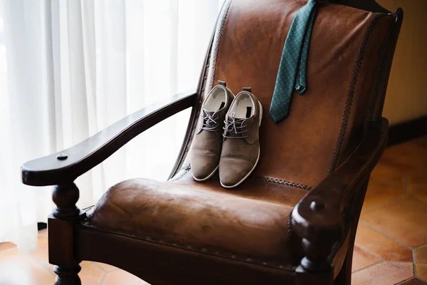Poltrona de couro genuíno em uma sala com sapatos masculinos e um empate. — Fotografia de Stock