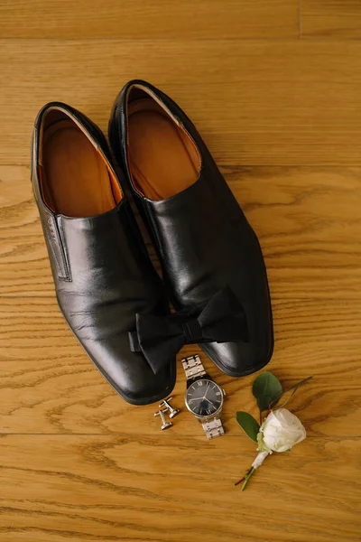 Sapatos pretos dos homens e gravata borboleta na textura de madeira com abotoaduras, relógio de pulso e branco rosa noivo boutonniere. — Fotografia de Stock
