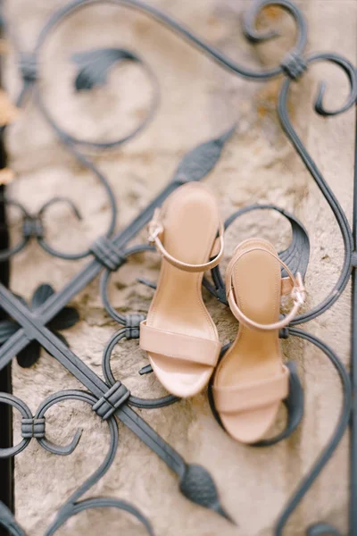 Beige brides sandal pada pagar logam dengan pola hiasan. — Stok Foto
