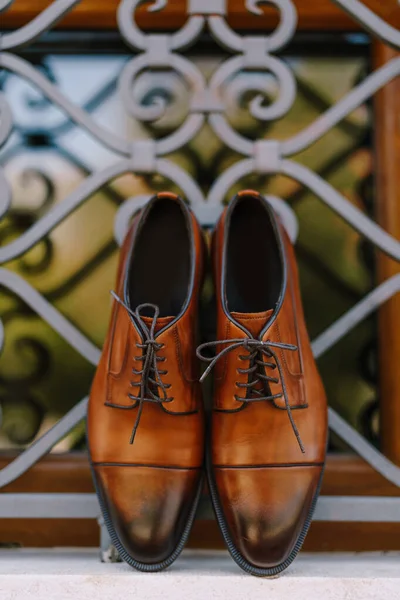 Um close-up de novos sapatos dos homens marrons contra as barras de metal da janela. — Fotografia de Stock