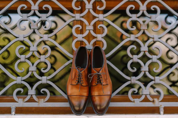 Homens sapatos castanhos elegantes feitos de couro genuíno pela janela com uma treliça de metal. — Fotografia de Stock