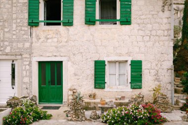 Karadağ cephesinde ahşap pencereli ve çiçekli eski bir binanın yeşil kapısı.