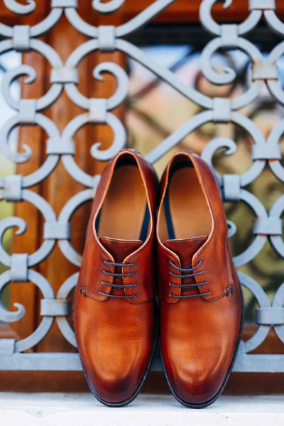 Novos sapatos dos homens marrons pela janela com barras de metal com profundidade rasa de campo. — Fotografia de Stock