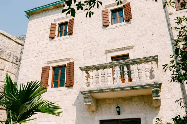 Hermoso balcón antiguo en un edificio de piedra clara con persianas de madera. — Foto de Stock