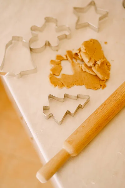 O processo de fazer biscoitos de gengibre - rolo de pino, moldes e massa em uma mesa branca. — Fotografia de Stock