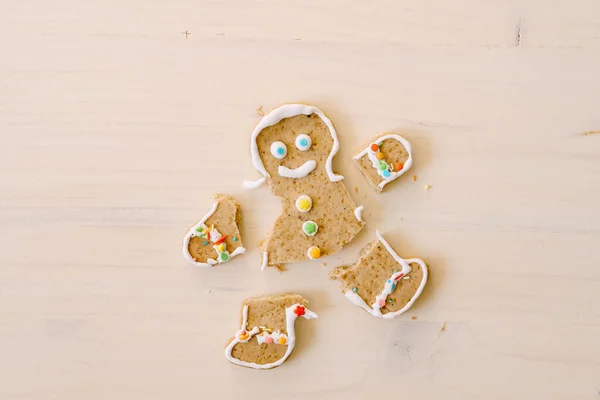 Homem de gengibre com pernas e braços cortados. Os membros do biscoito são separados do corpo. Pão de gengibre de Natal em um fundo de madeira branco. — Fotografia de Stock