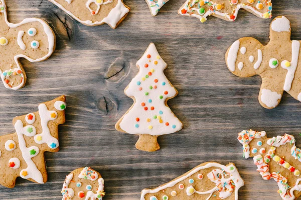 Крупный план рождественского пряничного печенья на деревянной текстуре. Пихты, маленькие человечки и колокола украшены белой глазурью с разноцветными точками. — стоковое фото