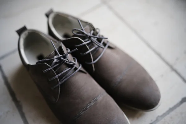 Scarpe uomo in camoscio grigio con lacci sul pavimento con bassa profondità di campo. — Foto Stock