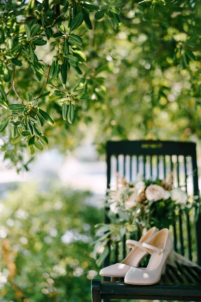 Una silla con zapatos y un ramo de novia bajo el árbol de semillas de resina con frutas en el árbol. —  Fotos de Stock