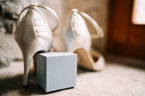 Primer plano de una caja de anillos con zapatos de novias blancas en una habitación con poca profundidad de campo. —  Fotos de Stock