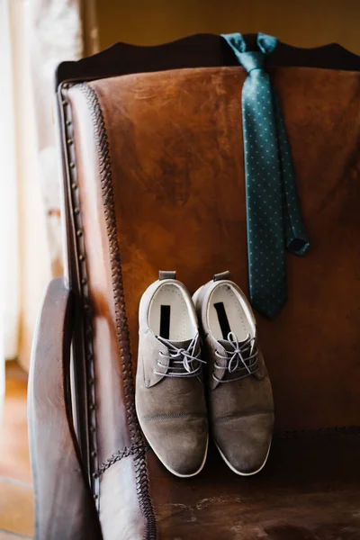 Sapatos de noivos e gravata de bolinhas em uma cadeira de couro na sala. — Fotografia de Stock