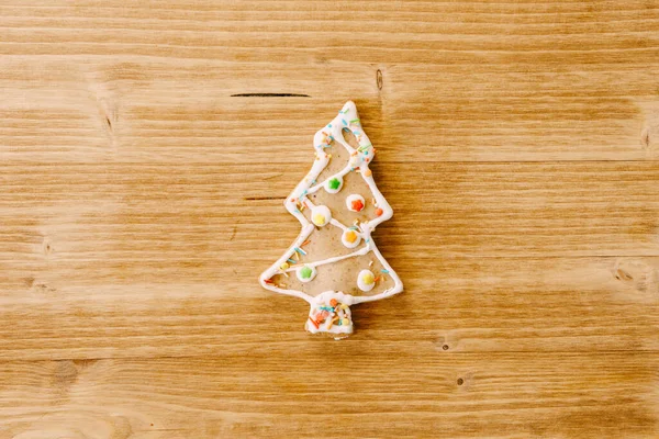 Пряничное печенье в форме рождественской елки, украшенной порошком на светлом деревянном фоне. — стоковое фото