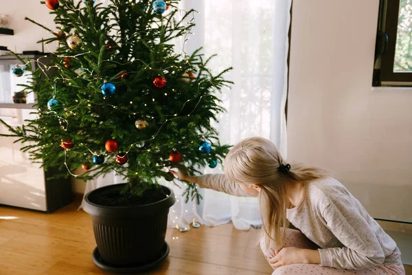 Seorang wanita menghias pohon Natal hidup di pot bunga. Stok Lukisan  