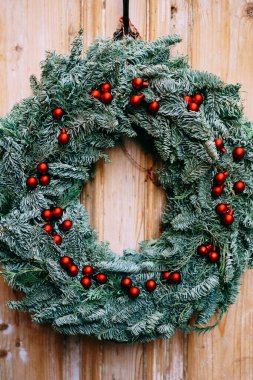 Kırmızı böğürtlenli köknar dallarından yapılmış bir Noel çelengi..