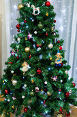 Detailní záběr slavnostně zdobeného vánočního stromečku s hračkami, míčky a girlandami.