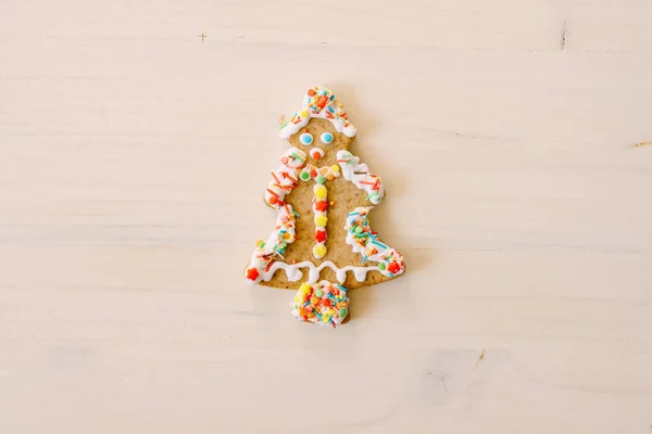 Biscoitos de gengibre em forma de árvore de Natal, decorados com esmalte e polvilhas coloridas, sobre uma textura de madeira pintada de branco. — Fotografia de Stock