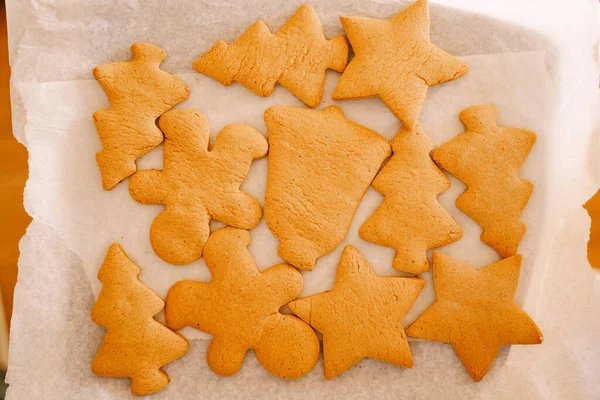 Nybakat hembakat pepparkaksbakverk festligt tillagat hemma. Varmt ljus, selektivt fokus. Närbild av nybakade, nakna julpepparkakor utan glasyr på vitt bakpapper — Stockfoto