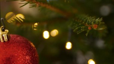 Ağaç dallarında kırmızı bir Noel topunun makro çekimi.