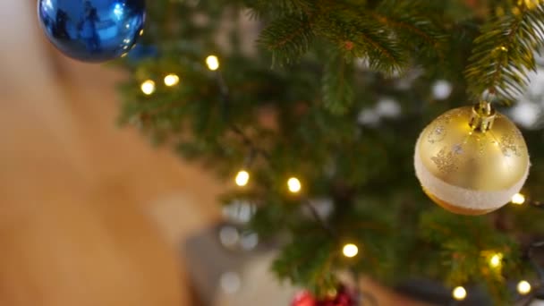 Close-up de uma bola de Natal dourada em um ramo de uma árvore de Natal. — Vídeo de Stock