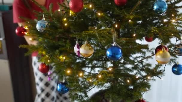 パジャマの女の子は鍋にクリスマスツリーを飾る. — ストック動画