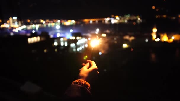 ไฟเบงกอลในมือในเวลากลางคืนบนพื้นหลังของไฟเมือง . — วีดีโอสต็อก