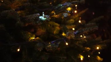 Noel arkaplanı. Karanlıkta gerçek bir Noel ağacının dallarında bir çelenk yanıp sönüyor..