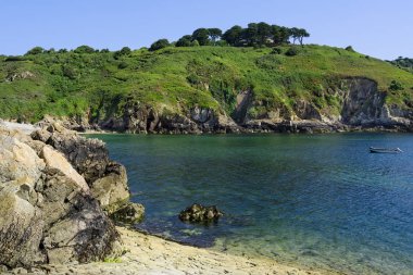 Mavi su ve engebeli kayalıklarla Saints Bay Harbour, Guernsey.