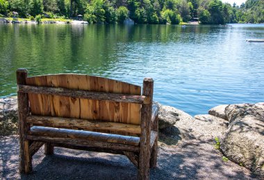 Empty wooden bench on the shoreline of Mohonk Lake, in upstate New York. clipart
