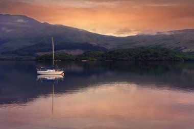 Bir gün batımında İskoçya, Lomond Gölü 'nde dinlenen yelkenli.
