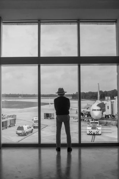 a man in the airport waiting the plain in the window