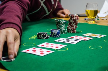 yeşil bir masada iskambil kartları ile poker yongaları
