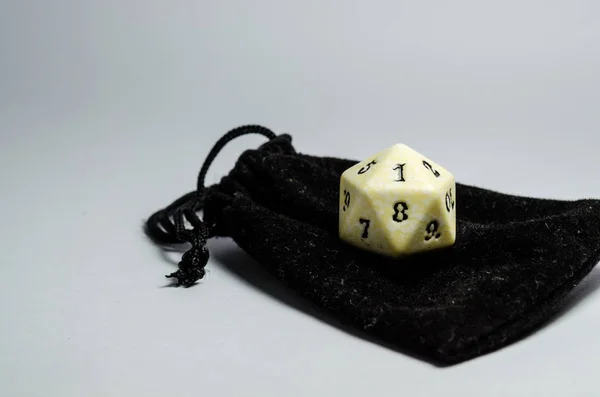white twenty-sided dice on a small black purse on a white background. Dice of role playing game and dungeons and dragons. top view.