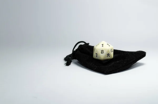 white twenty-sided dice on a small black purse on a white background. Dice of role playing game and dungeons and dragons. top view.