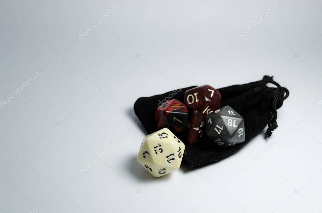 Some rpg dice grouped together on top of a small black purse isolated on a white background. Dices of role playing game and dungeons and dragons.