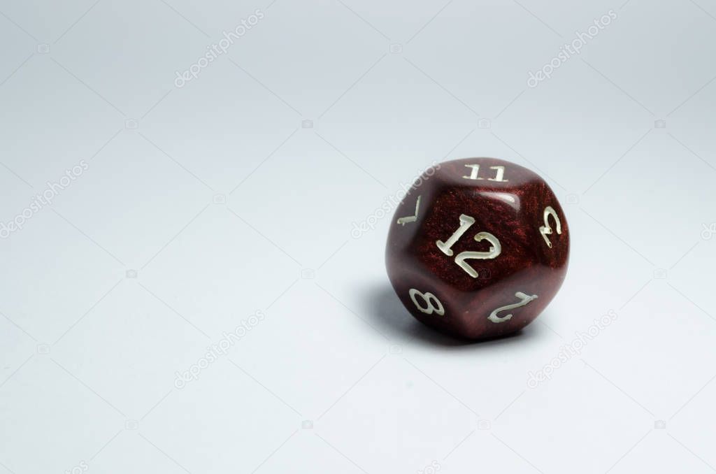 A red twelve-sided dice, isolated on a white background. Dice of role playing game and dungeons and dragons. number twelve in focus.