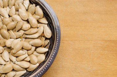 Hafif ahşap yüzeyüzerinde küçük bir kase içinde kabak çekirdeği.