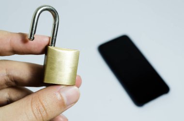 Cep telefonlarında güvenliğin kavramsal fotoğrafı. Arka planda açık bir asma kilit ve cep telefonu tutan el